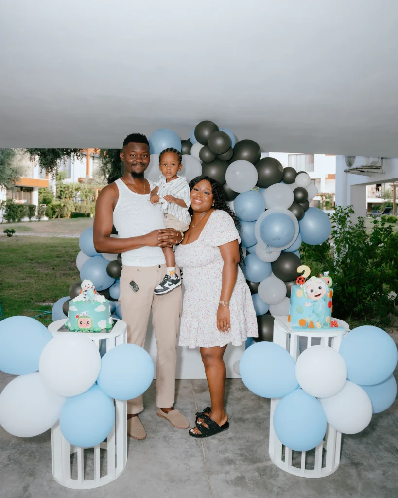 Family celebrating a child's birthday outdoors with balloons